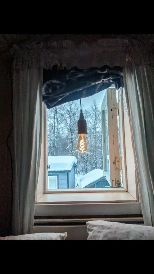 Leuchtende Glühbirne hängt vor einem Fenster